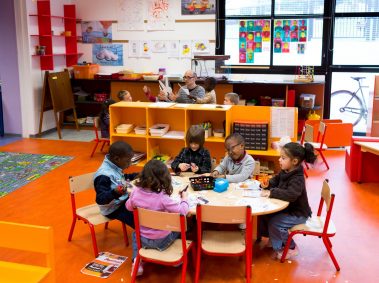 école maternelle, enfants assis autour d'une table en train de faire du collage