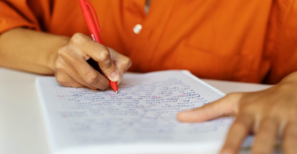 une personne corrige un texte écrit à la main sur un cahier